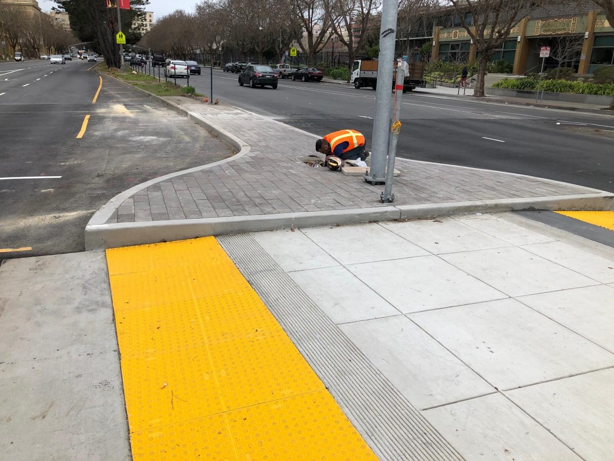 Photo showing worker finishing electrical work at new median bulb-out on Geary and Steiner