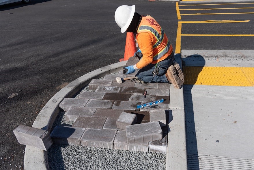 Photo of a crew member laying new pavers in the center median at Geary and Steiner streets.