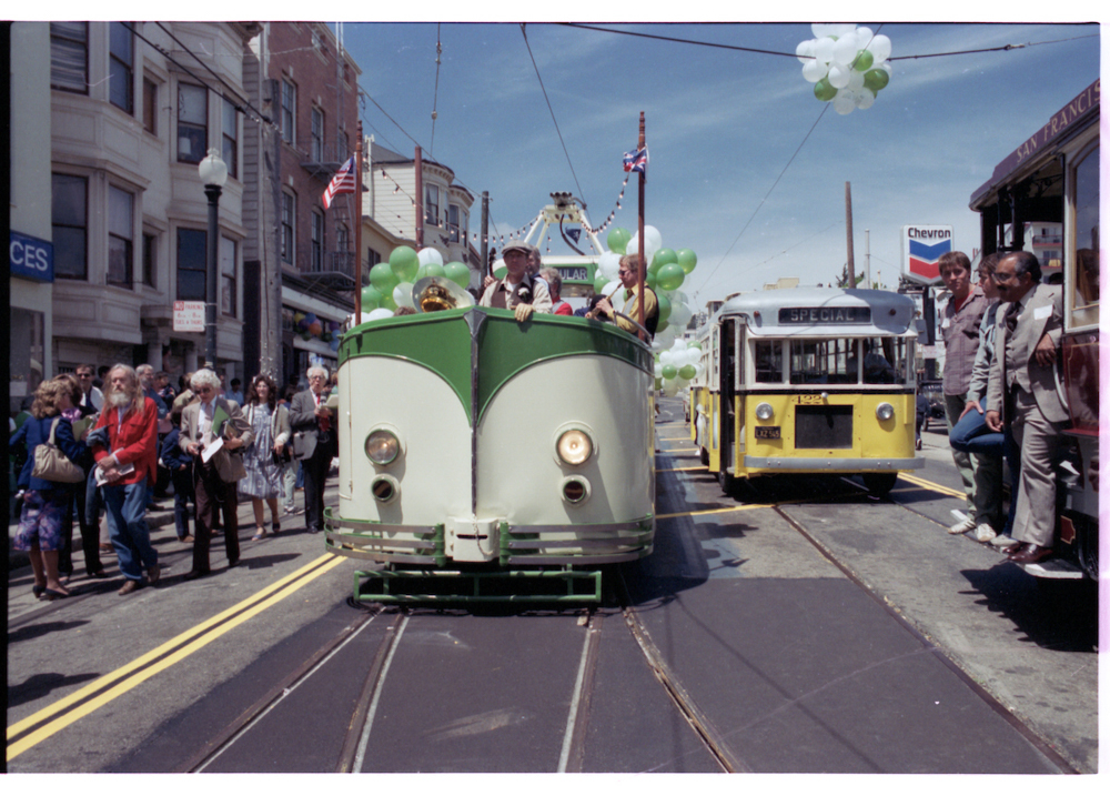 vintage streetcars and buses on street with people around