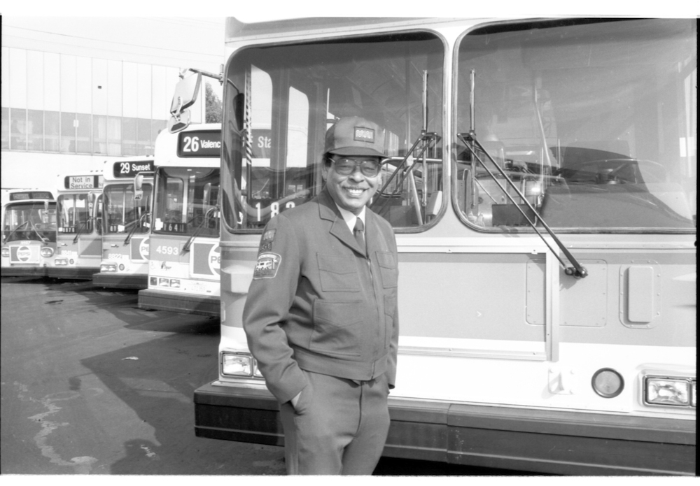 person standing in front of row of buses smiling
