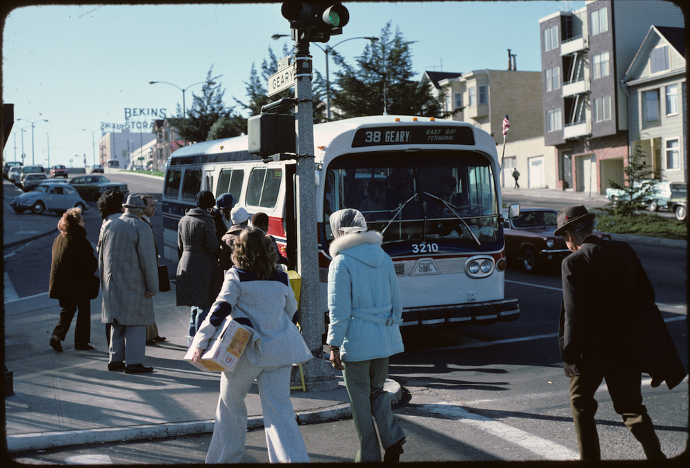 Passengers boarding 38 Geary bus with red white and blue paint scheme