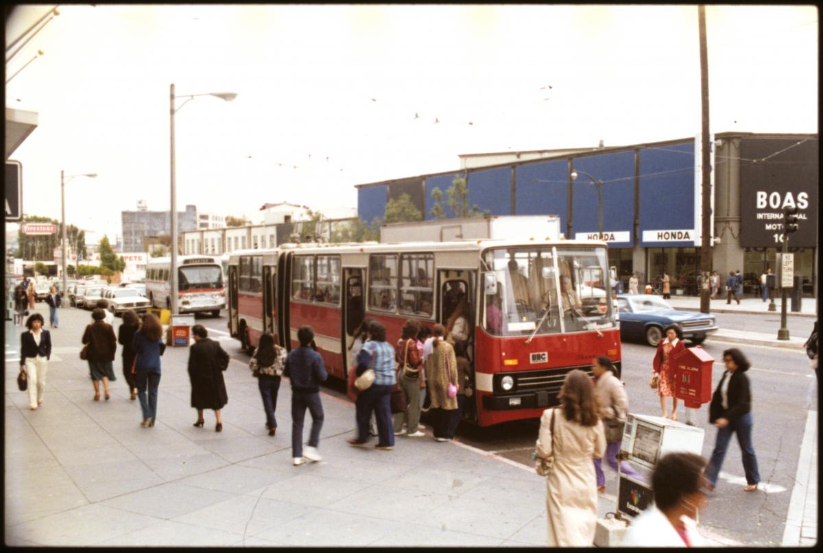 People boarding a Ikarus Articulating Bus on South Van Ness Avenue at Market Street