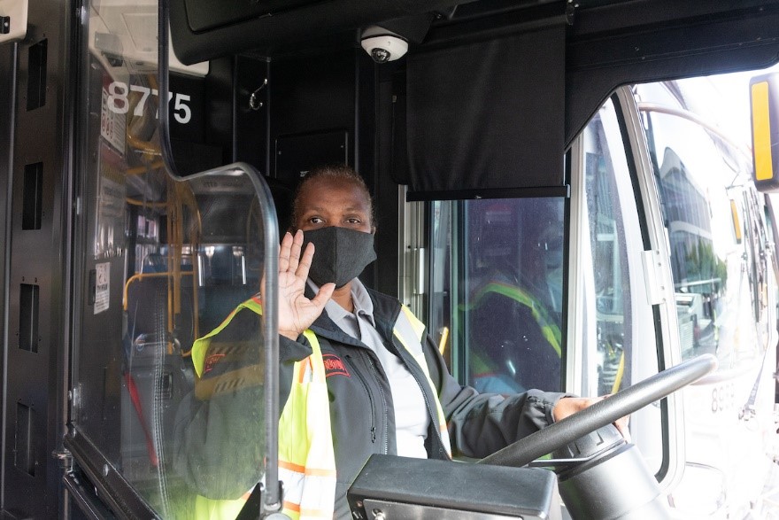 Photo of muni operator behind the wheel, wearing a mask