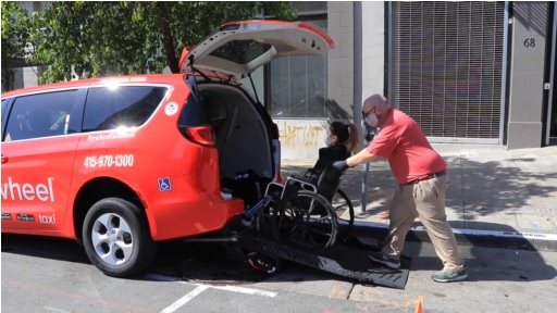 Photo of taxi driver assisting wheelchair user enter into the vehicle