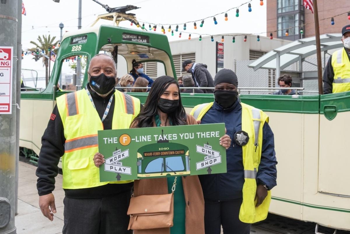 Photo of SFMTA Staff holding "F Line Takes You There" sign
