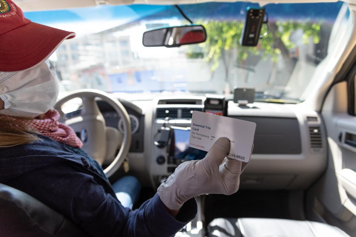 Photo of taxi driver holding essential trip card voucher