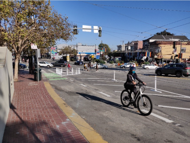 Image of a person riding a bike on Market St just west of Castro St in a partially-protected bikeway