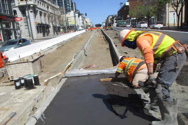 Photo of workers smoothing concrete in the median on Van Ness Avenue
