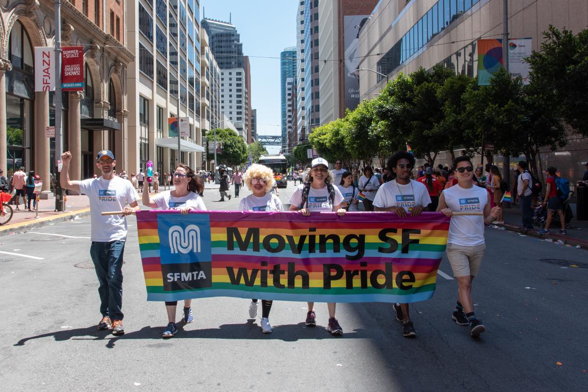 MTA participants holding a banner displaying "Moving SF with Pride" in the Pride Parade on city streets 