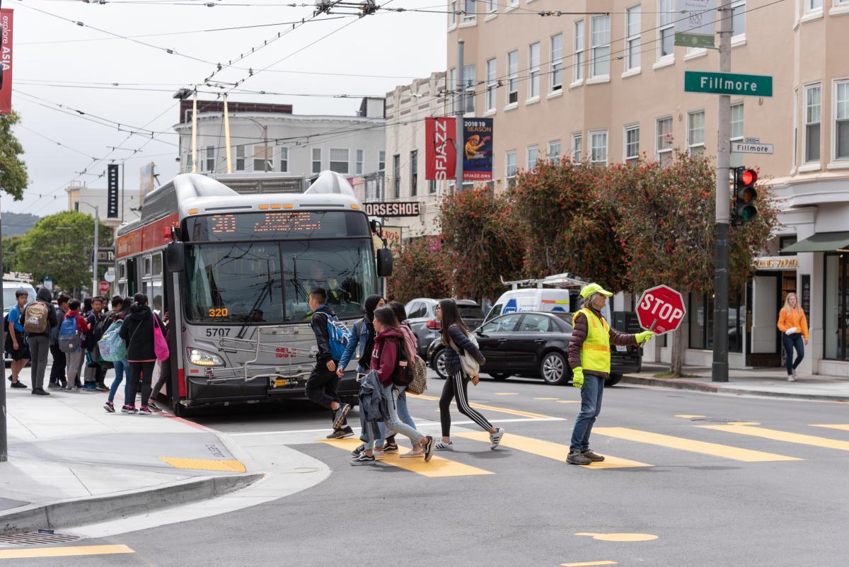 Students boarding the 30 Stockton bus, as well as crossing the street to catch the bus. 