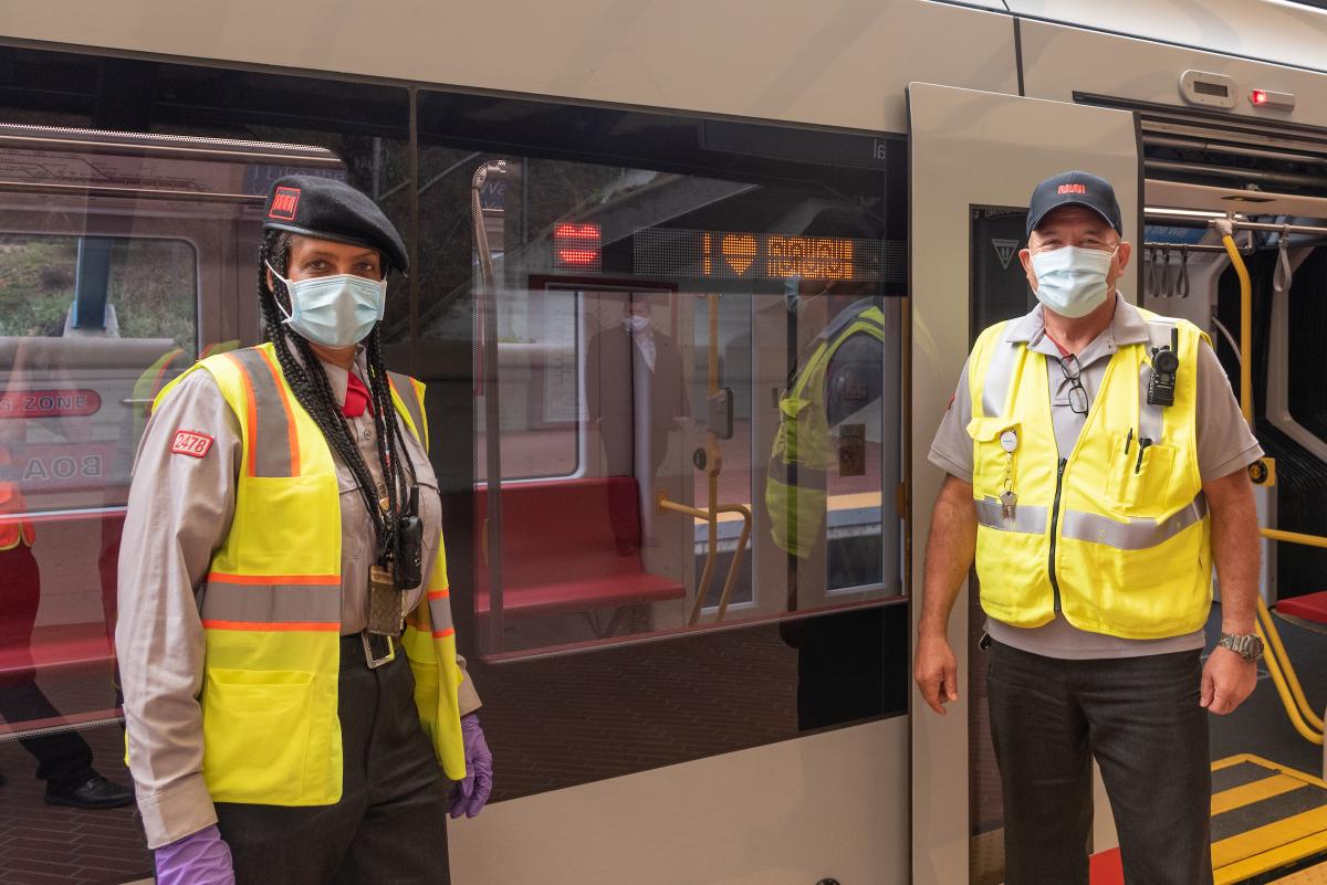Image shows two Muni operators standing in front of an LRV4 train
