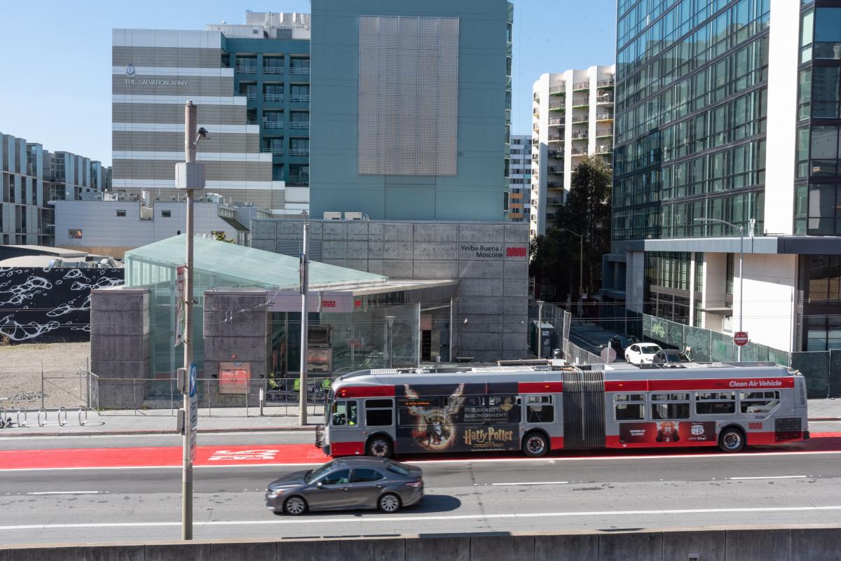 A zoomed out image of bus traveling down the bus lane in front of the new Yerba Buena/Moscone station.