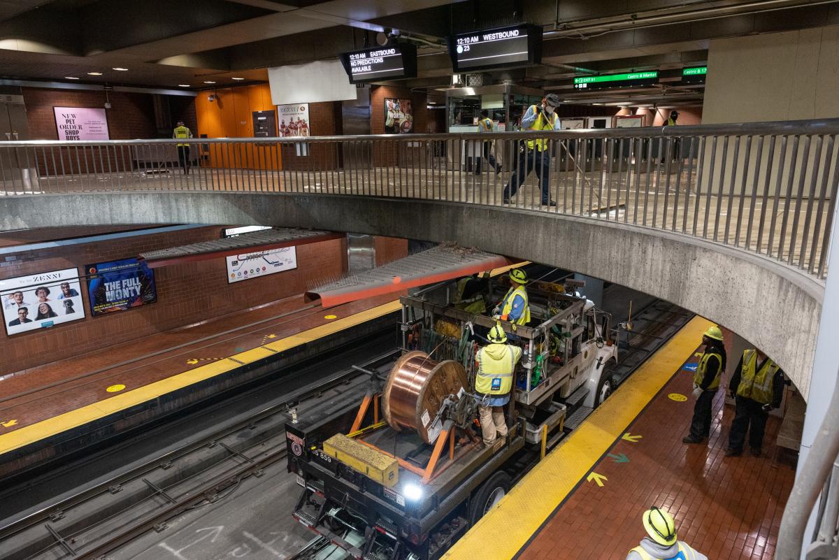 Overhead Line crew replacing wire and custodians cleaning metro station