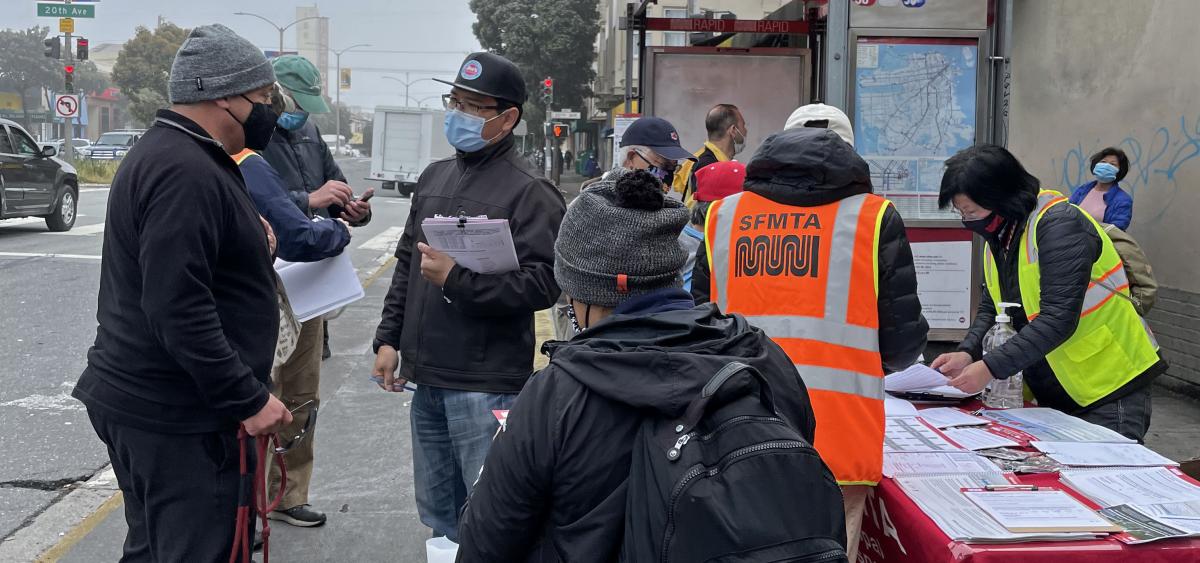 Image of pop-up outreach event on Geary and 20th Avenue. SFMTA staff are showing members of the publci project drawings and passing out surveys.