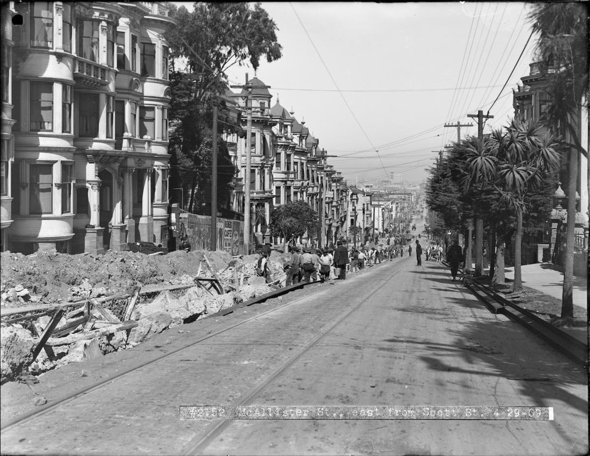 Laborers dig cable car “yokes” out of the street on McAllister between Scott and Pierce streets. Yokes are heavy steel frames that support both the rails and the cable channel on a cable car trackway. 