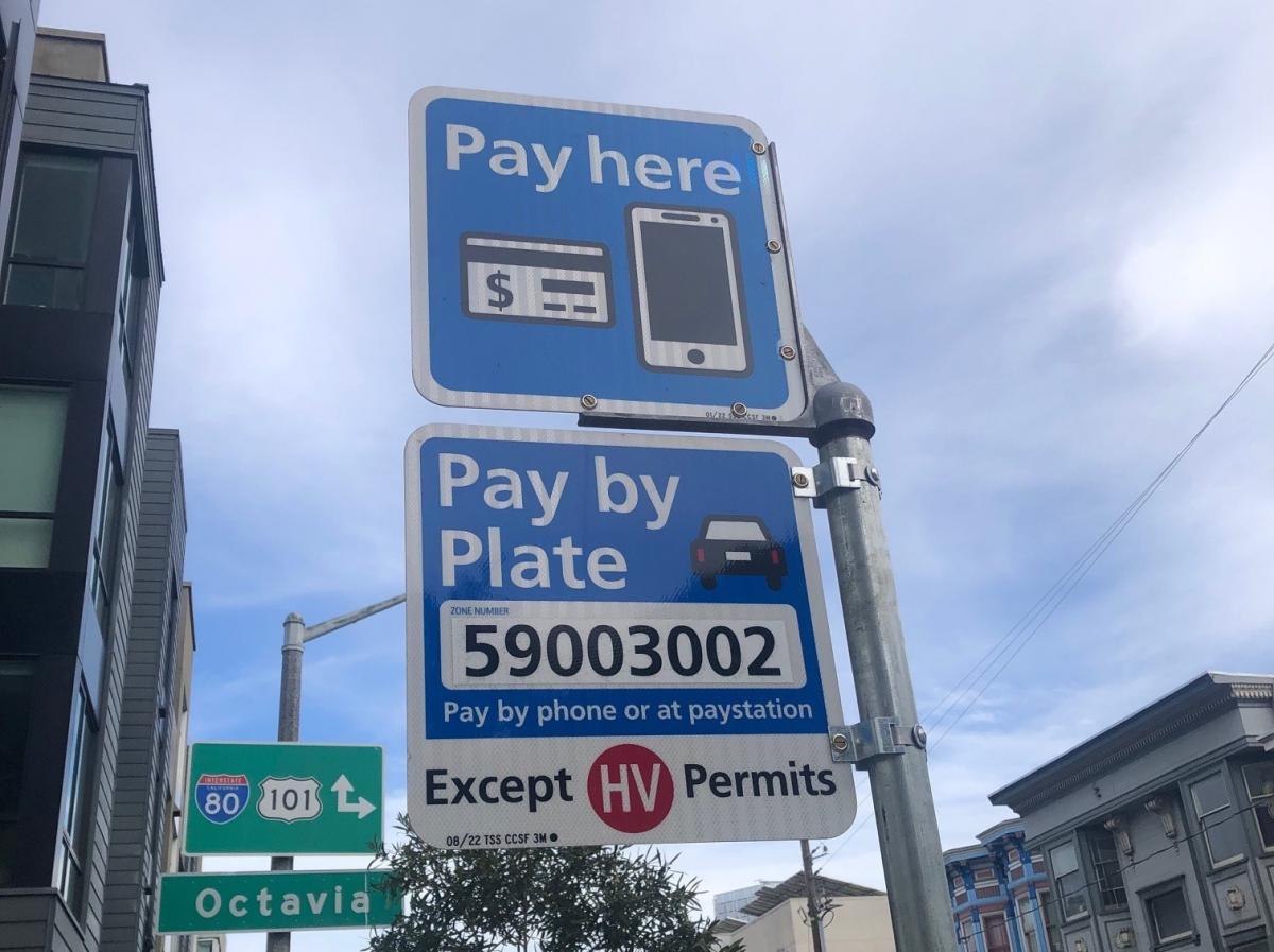 photo of two signs, one says "pay here", the other says "Pay by Plate zone number 59003002 Pay by phone or at paystation except HV permits"