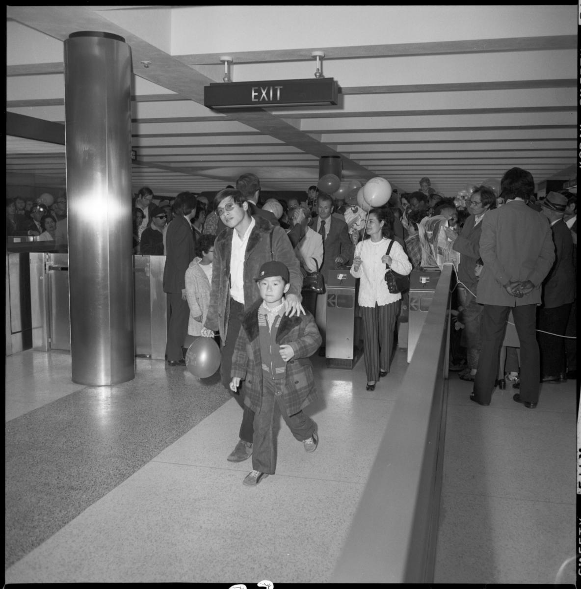 People entering fare gates inside station, some carrying balloons