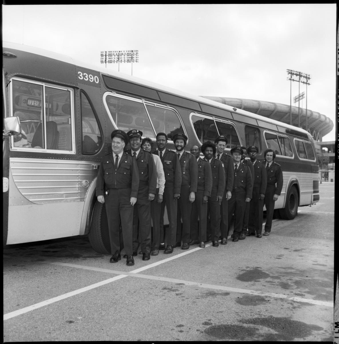 a team of operators lined up in front of a vintage bus outside in the parking lot 