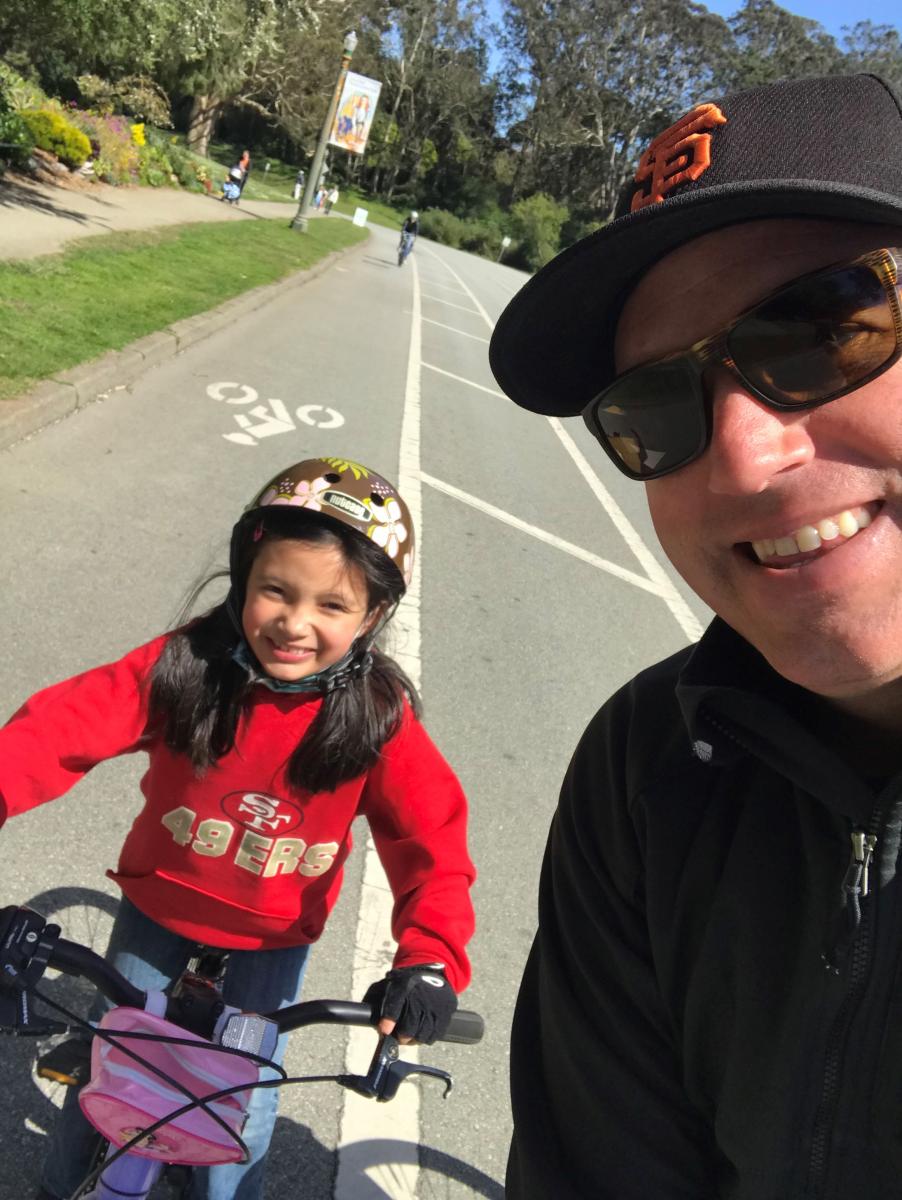 Mike Sallaberry and his daughter smiling on their bikes in Golden Gate Park