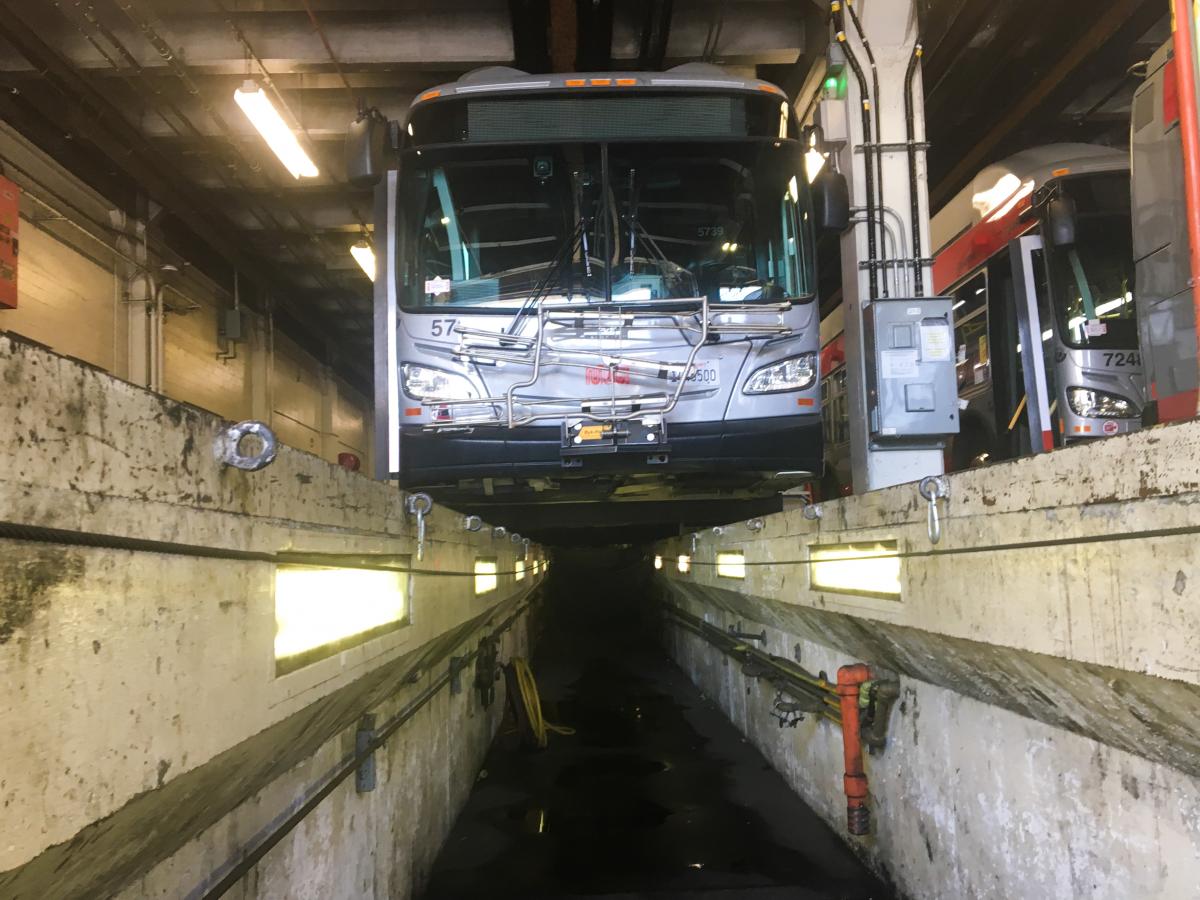 alt="A low-angle view of one of the trenches used to work on the undercarriages of the trolley buses at Potrero Yard. Fall, 2021. "