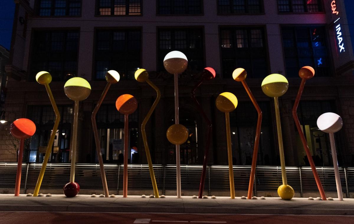 A light sculpture of colorful round orbs of light on bent and angled colored poles installed at Van Ness and O’Farrell streets