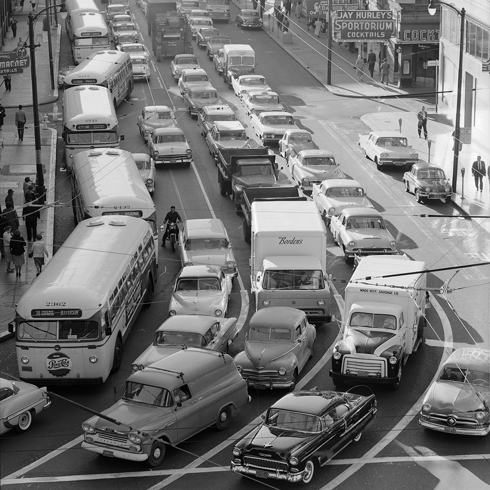 Cars and buses seen traveling during the busy commute on a congested street. 