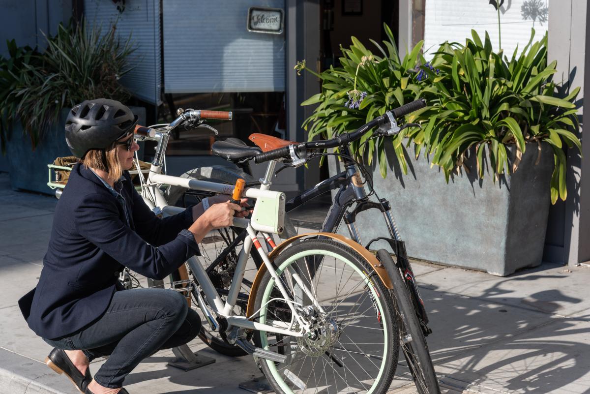 Bicyclist kneeling while locking up their bike 