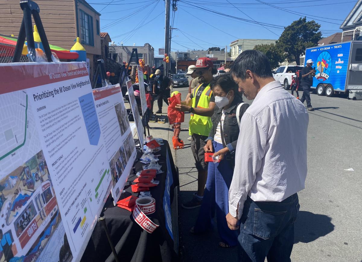 Participants at the OMI Roller Skate Party view project designs and talk to SFMTA staff.