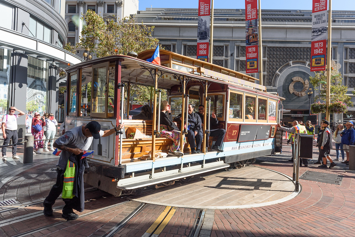 A cable car is rotated at the Powell Plaza turnaround by SFMTA operators.