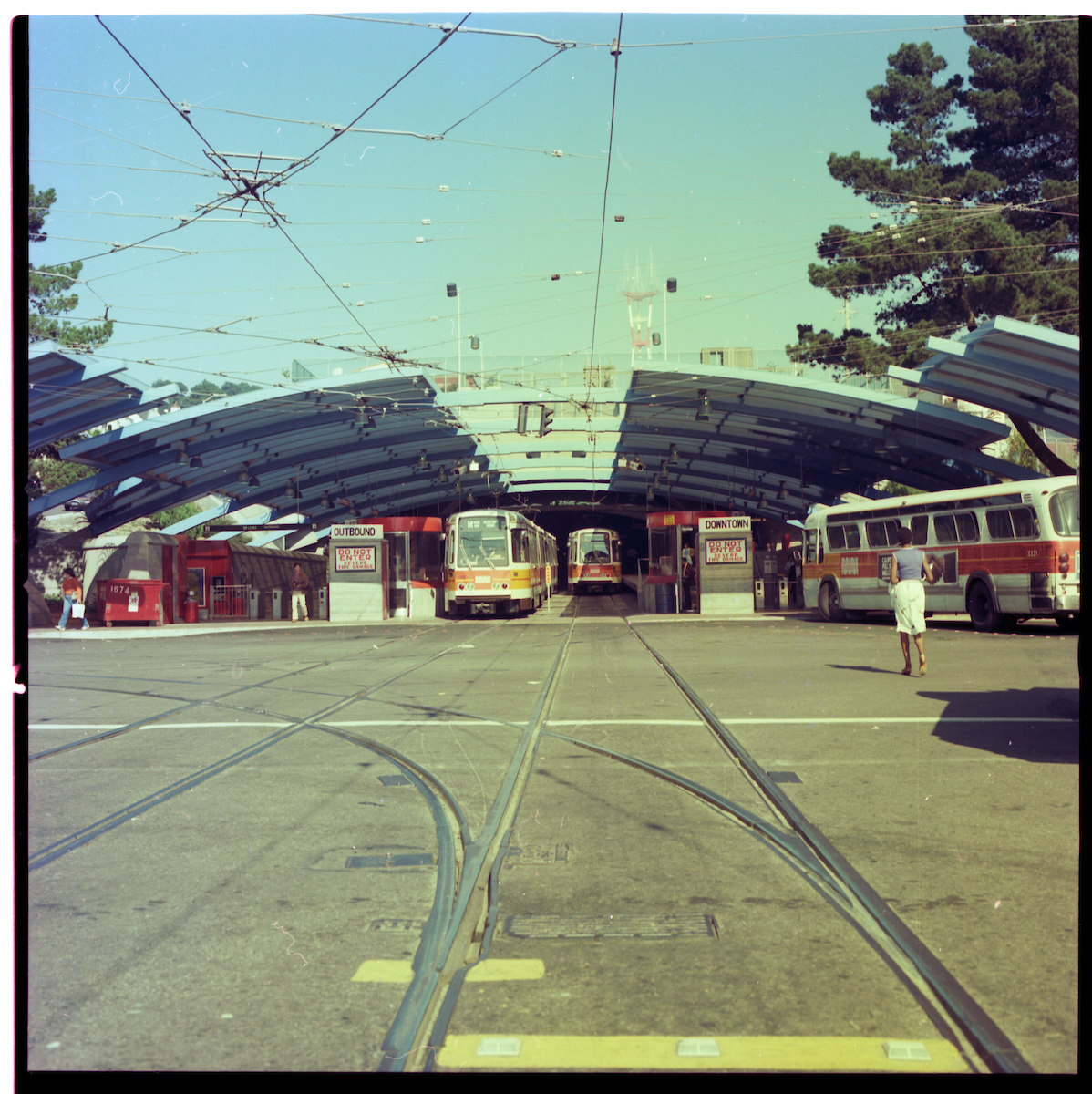 A colorized vintage photo of two subway trains at the tunnel entrance of West Portal station in San Francisco