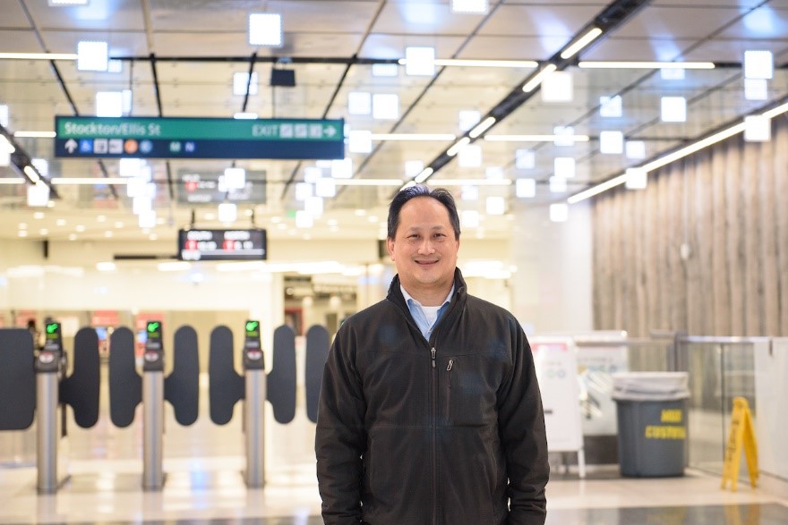 A man in a black jacket standing in a subway station.
