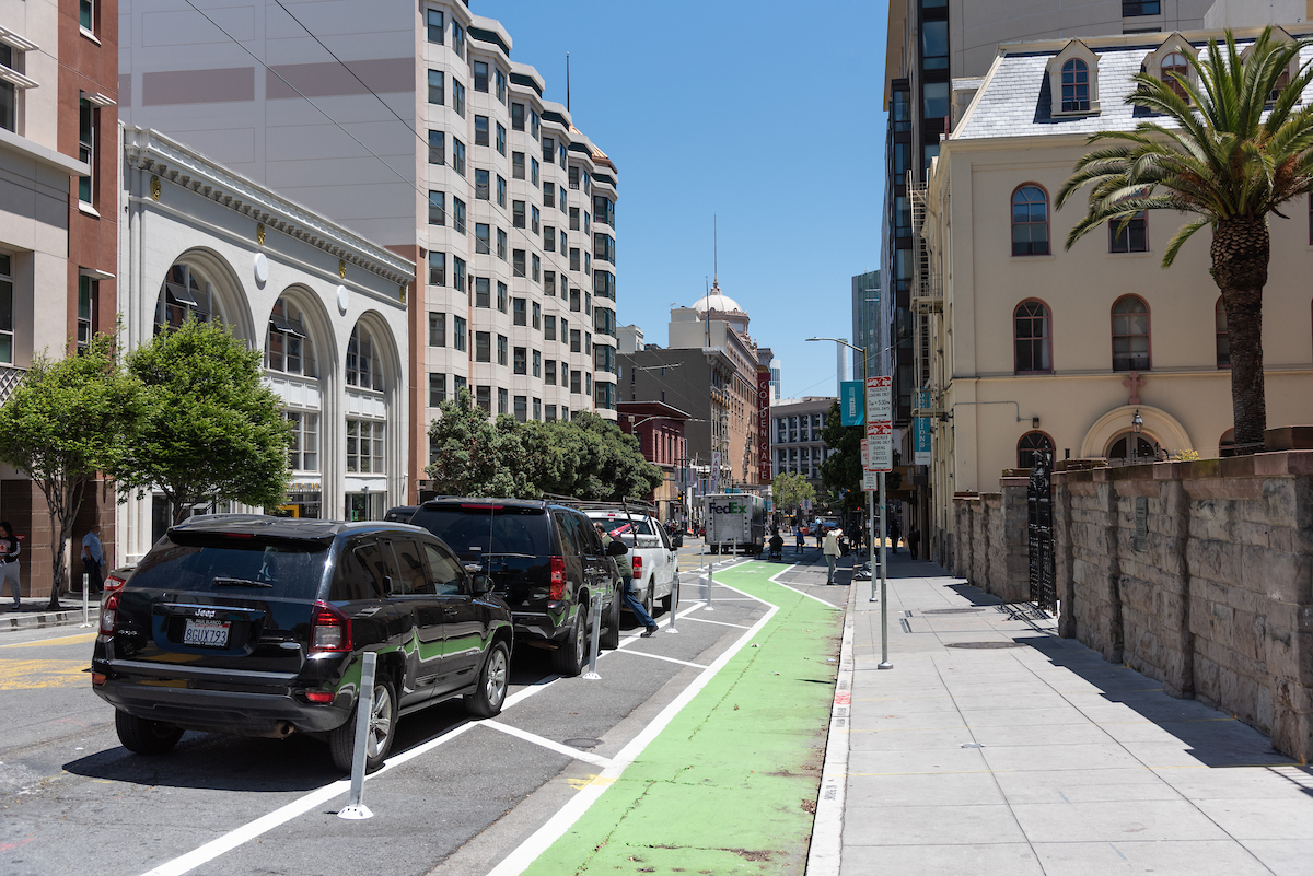 Image features a bike lane on Golden Gate Ave. The bikeway is painted green and separated from cars with plastic posts.
