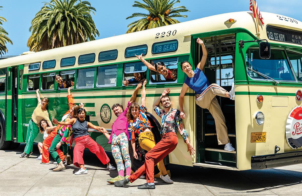 A group of people pose around a vintage bus.