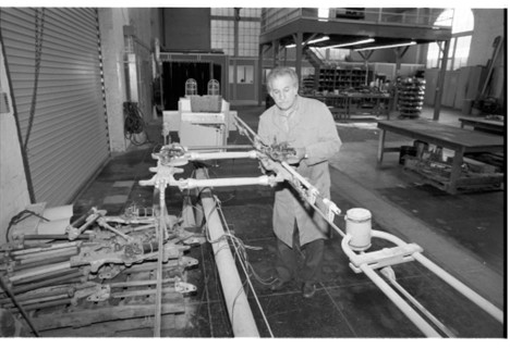 A black and white photo of a man doing repair work in a workshop