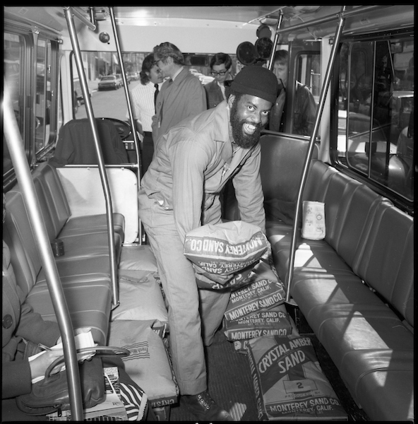 A black and white photo of a person loading sandbags into a bus.