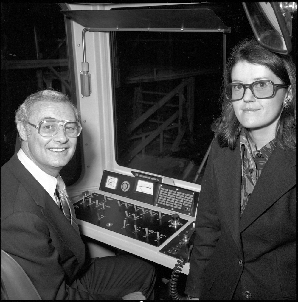 black and white photo of Mayor George Moscone seated at controls of Muni LRV with SFPUC Commissioner Claire Pilcher standing