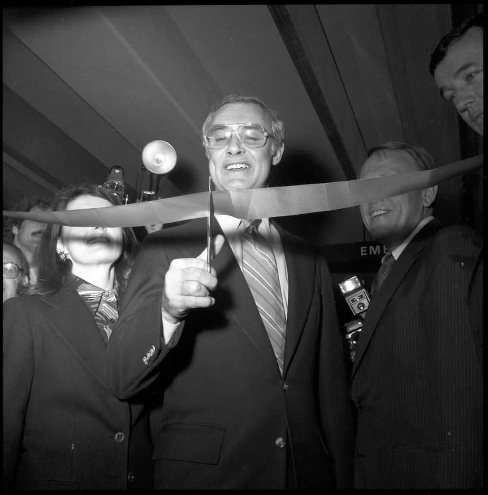 black and white photo of Mayor George Moscone cutting ribbon with scissors