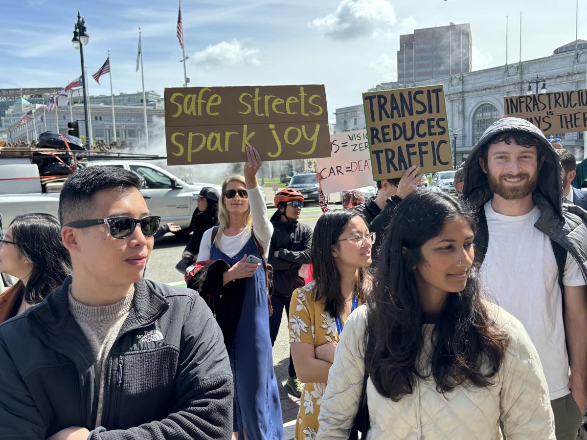 People on a sidewalk, some holding signs.