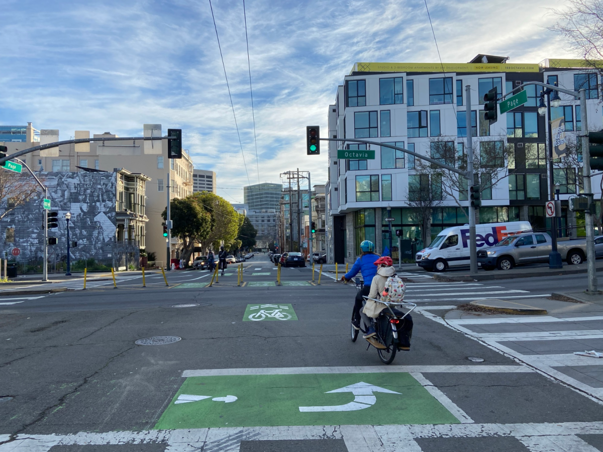 Image of Median Diverters in the middle of intersection and person on bike with a child waiting for the light at the intersection.