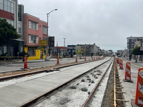 A rail track under construction with orange bollards on each side.