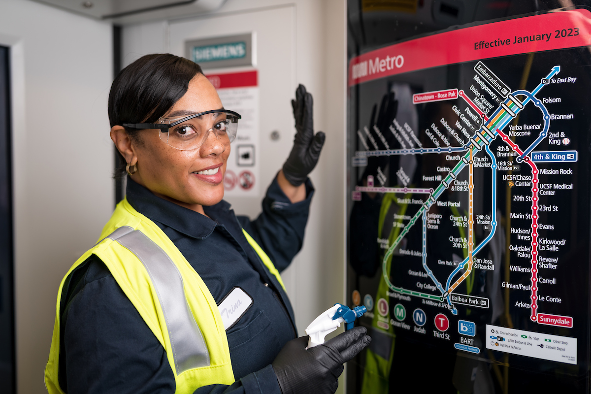 Trina Dixon smiles as she cleans the colorful Muni Metro map on a train.