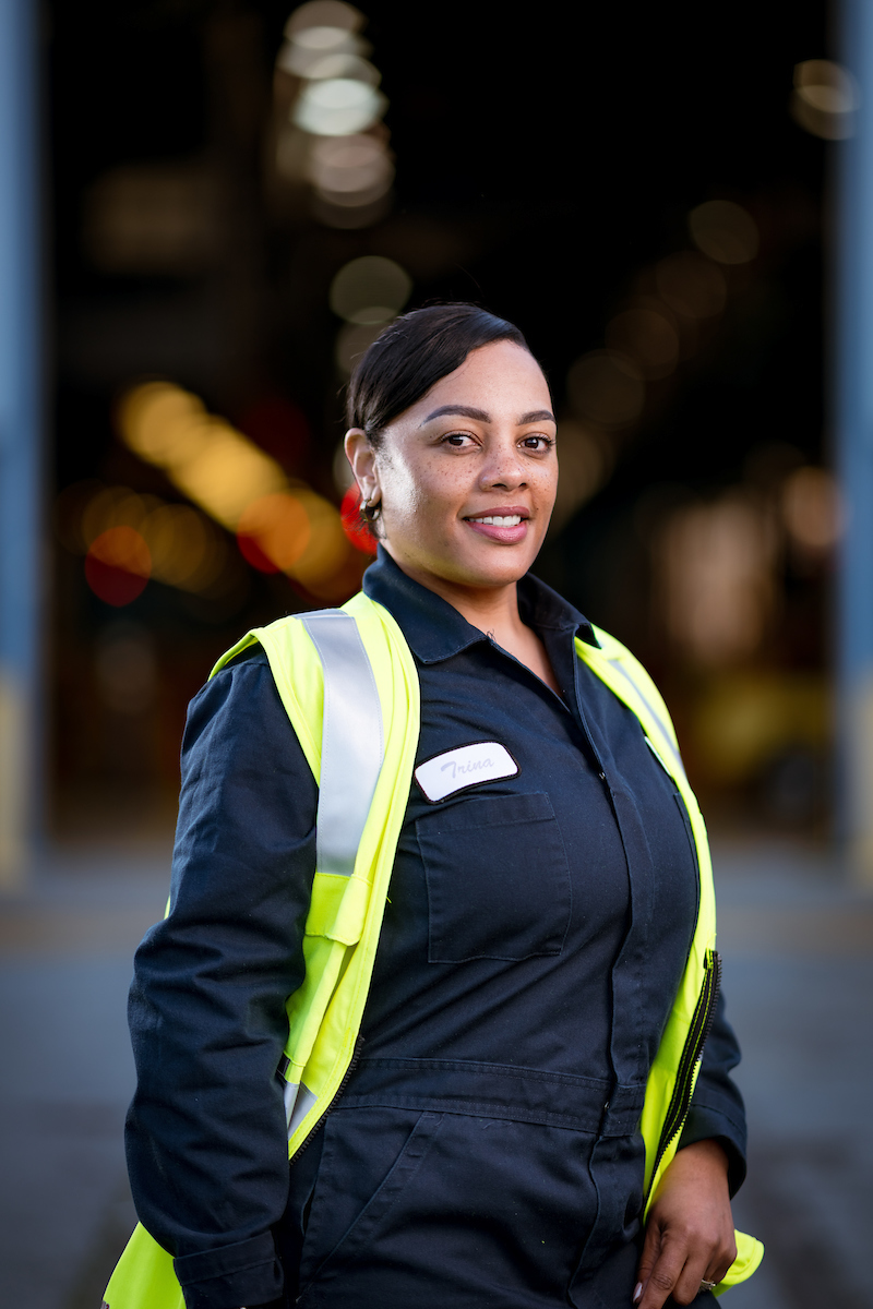 Trina Dixon wears a dark blue uniform and yellow safety vest, standing at her division.