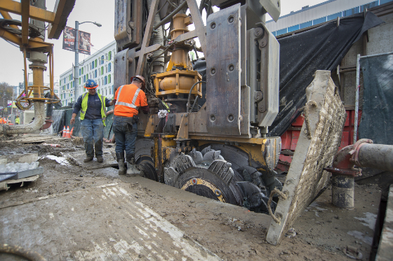 Two workers use a hydromill to build walls for the future Yerba Buena/Moscone Station.