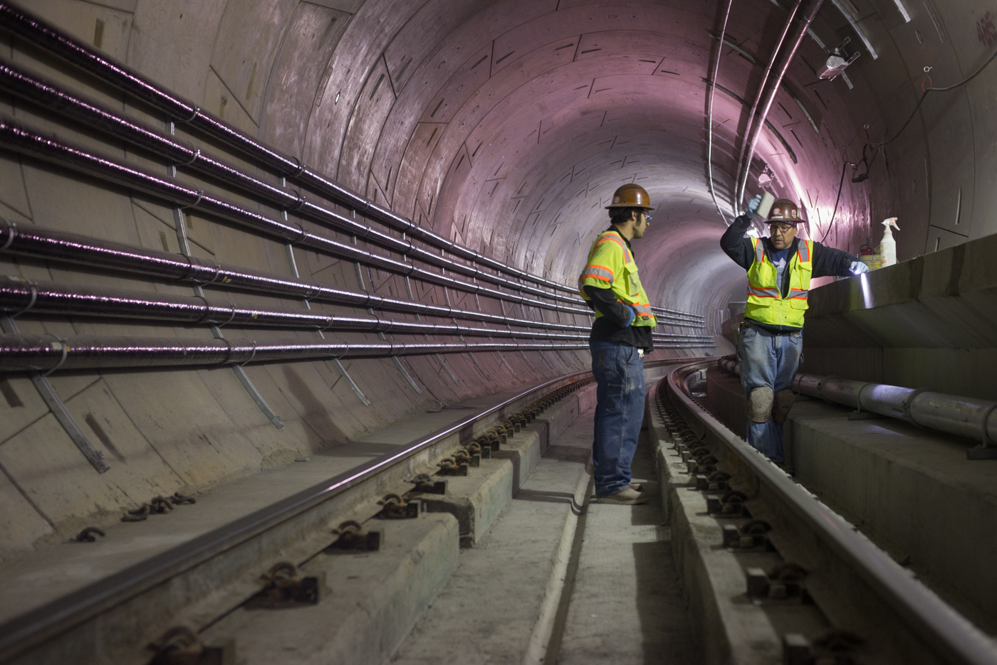 A worker demonstrates to an associate techniques for smoothing the edge of the northbound tunnel walkway