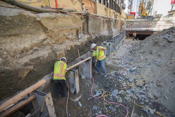 Workers remove excess<br />
    concrete around steel I-beams.