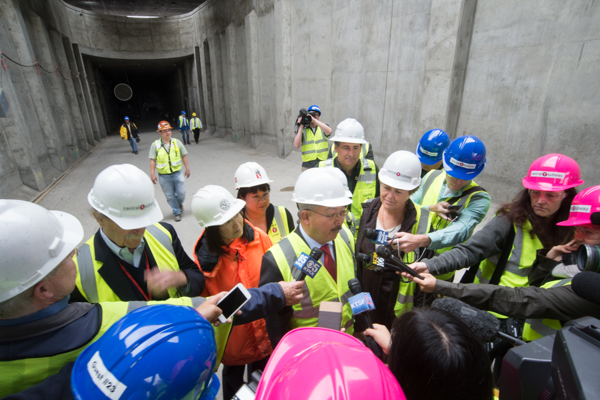 Members of the media hold microphones in front of Mayor Lee, who is flanked by SFMTA Chairman Tom Nolan, SFMTA staff and Supervisor Julie Christensen