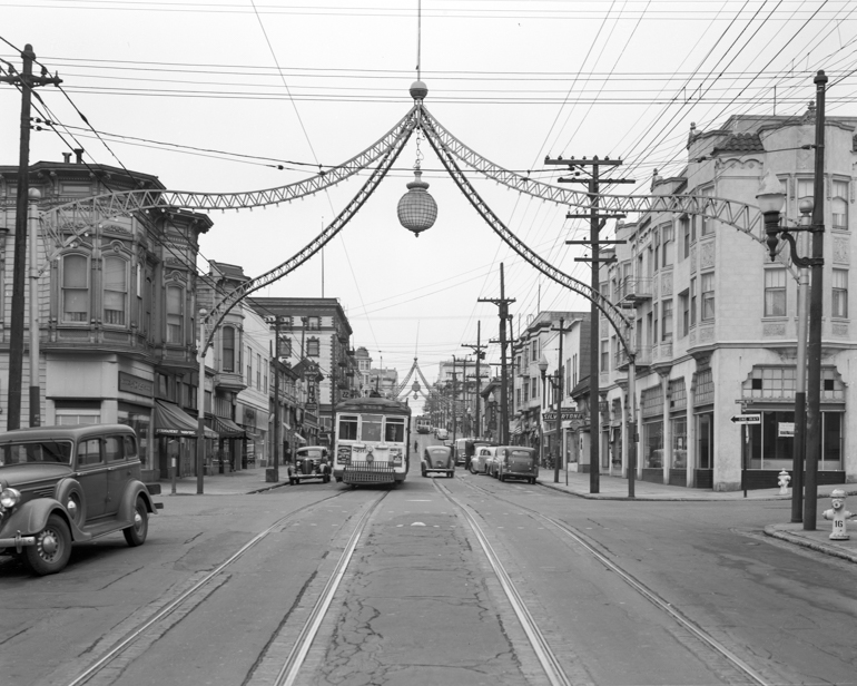 Looking north on Fillmore and Sutter streets at streetcar and ironwork arches above intersections.