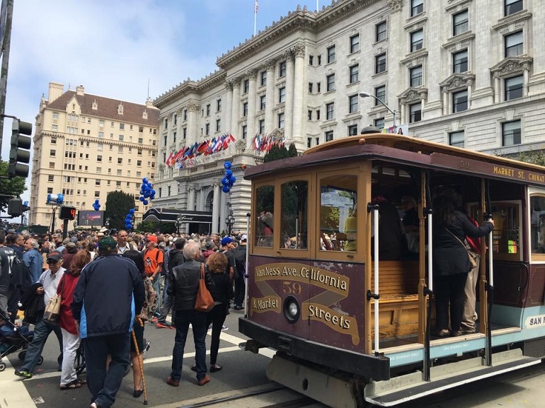 A crowd gathers in next to California Cable Car 52 on California at Masonic in front of the Fairmont Hotel.