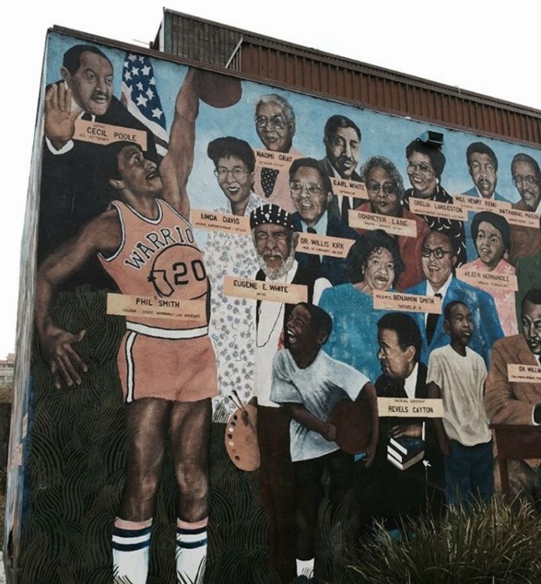 A painted mural on an outer wall of the Ella Hill Hutch Community Center features images of community members. Phil Smith is depicted dunking a basketball.