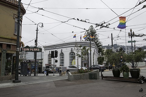 Intersection of Castro and Market streets with Muni overhead catenary wires above, the "Twin Peaks Tavern" sign and the rainbow flag.